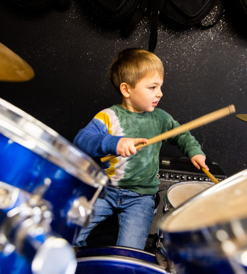 Young boy playing on a drumset.